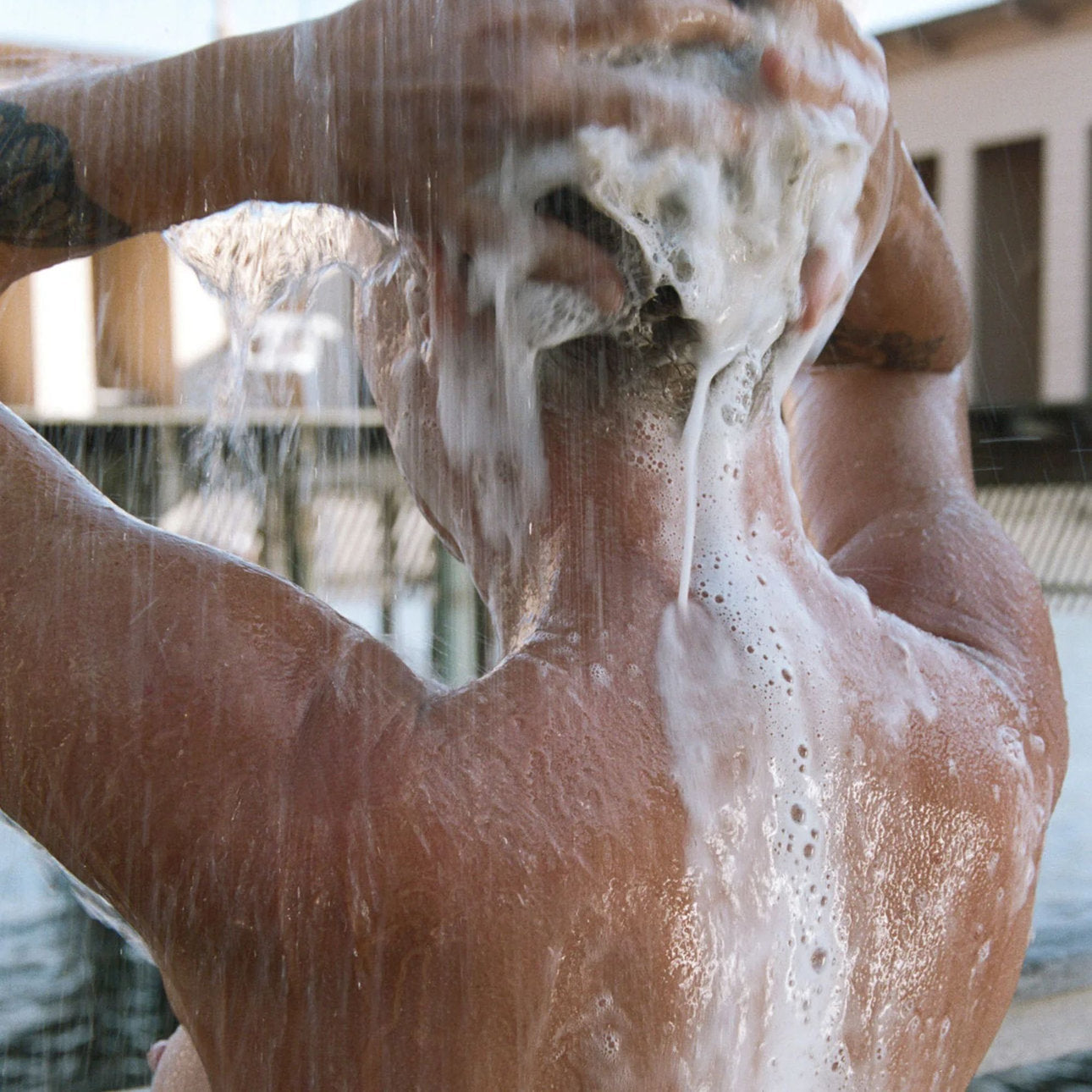 Einseifen von Schulter und Rücken unter der Dusche