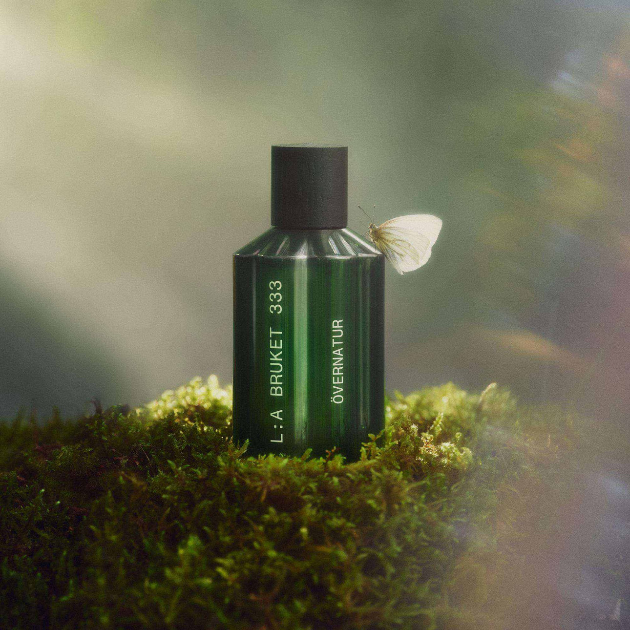 Eau-de-Parfum-Flakon auf Moos mit Schmetterling