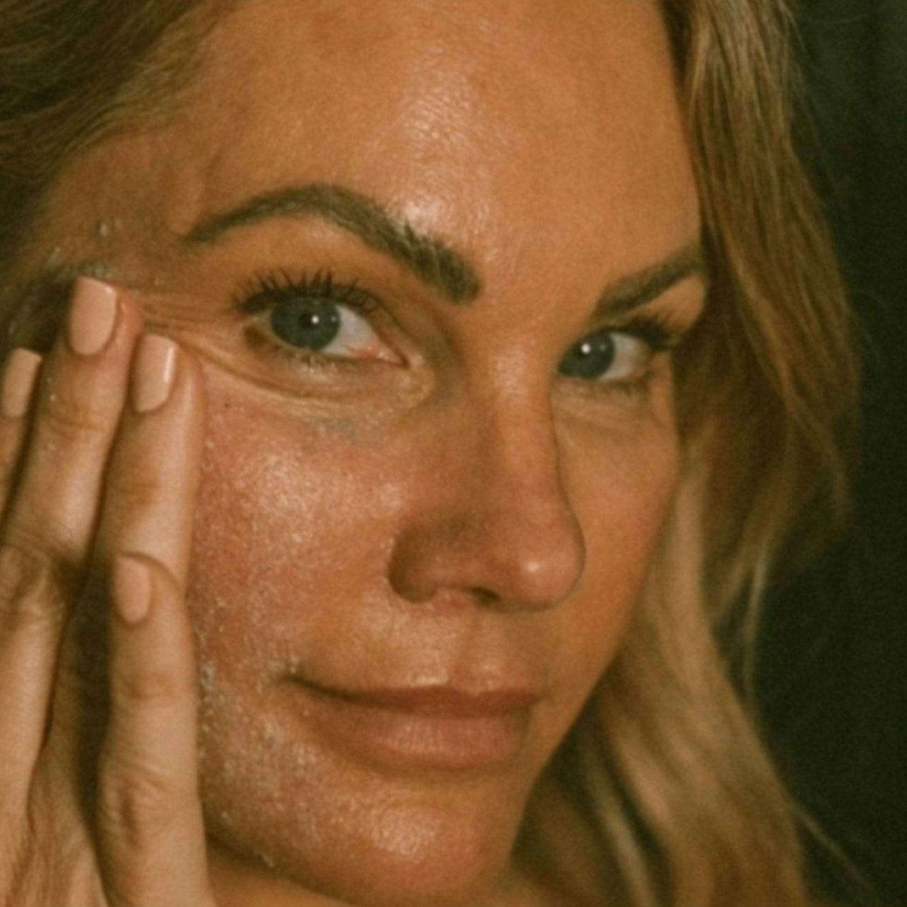 Frau massiert ein Peeling in die Gesichtshaut ein