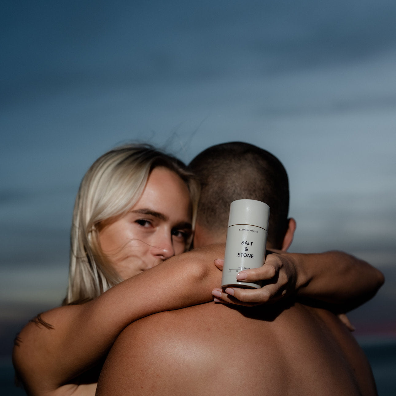 Umarmung, eine Hand hält einen Deo-Stick