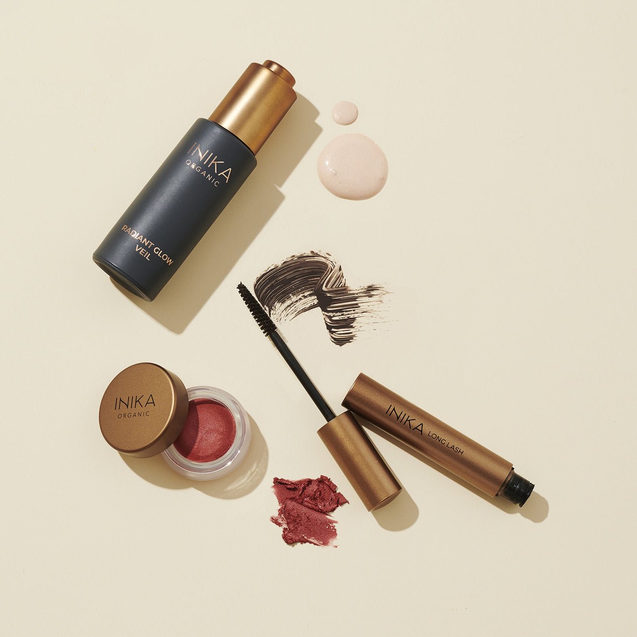 Flüssiges Make-up, Cremerouge und Applikator auf beigem Grund