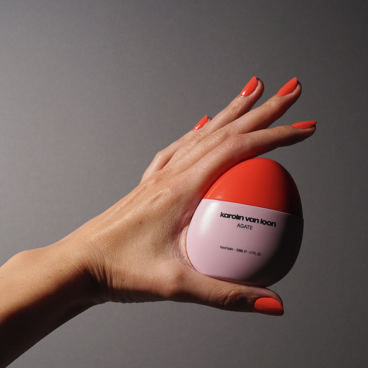 Hand mit lackierten Nägeln hält einen Handbalsam