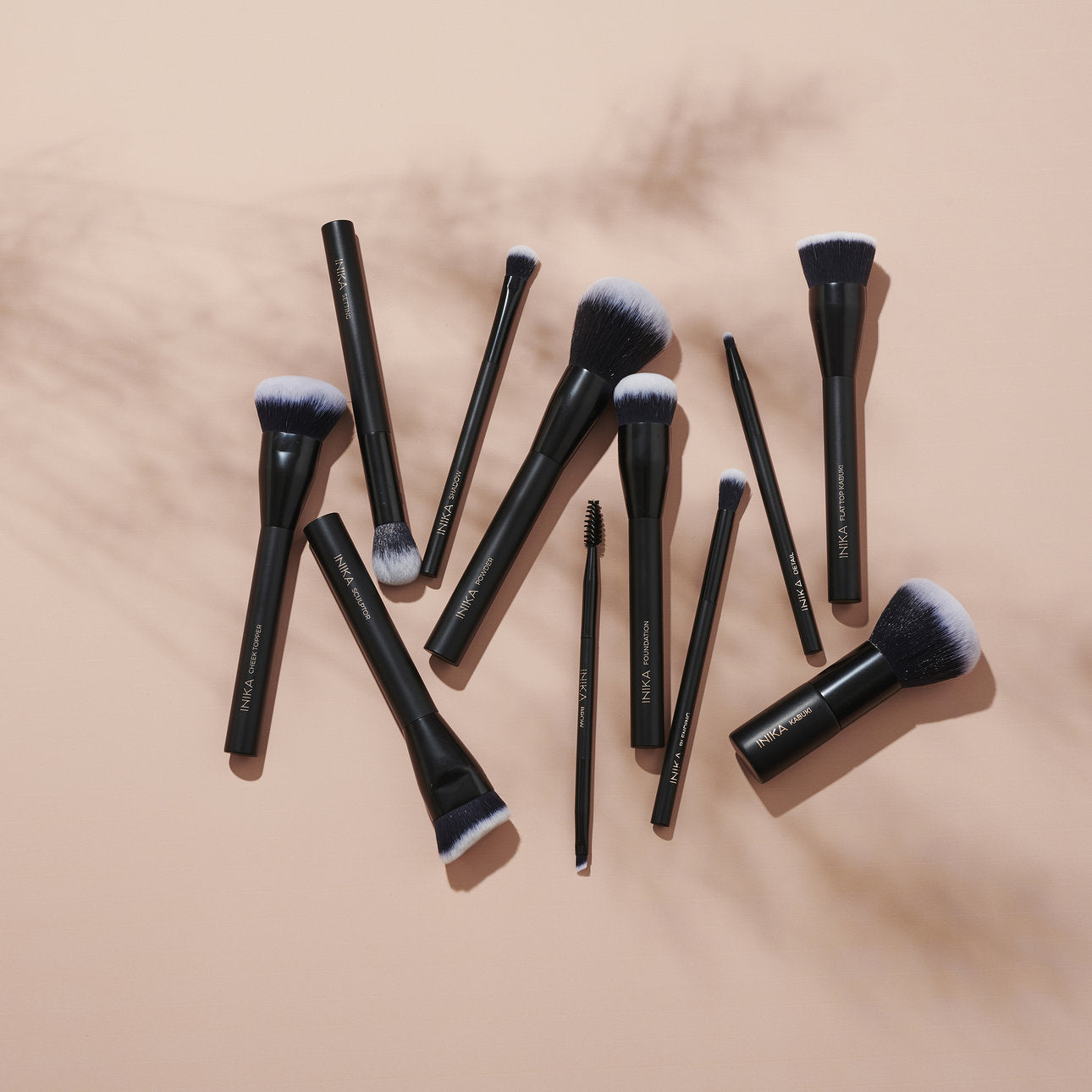 Verstreute Make-up-Pinsel auf altrosa Grund