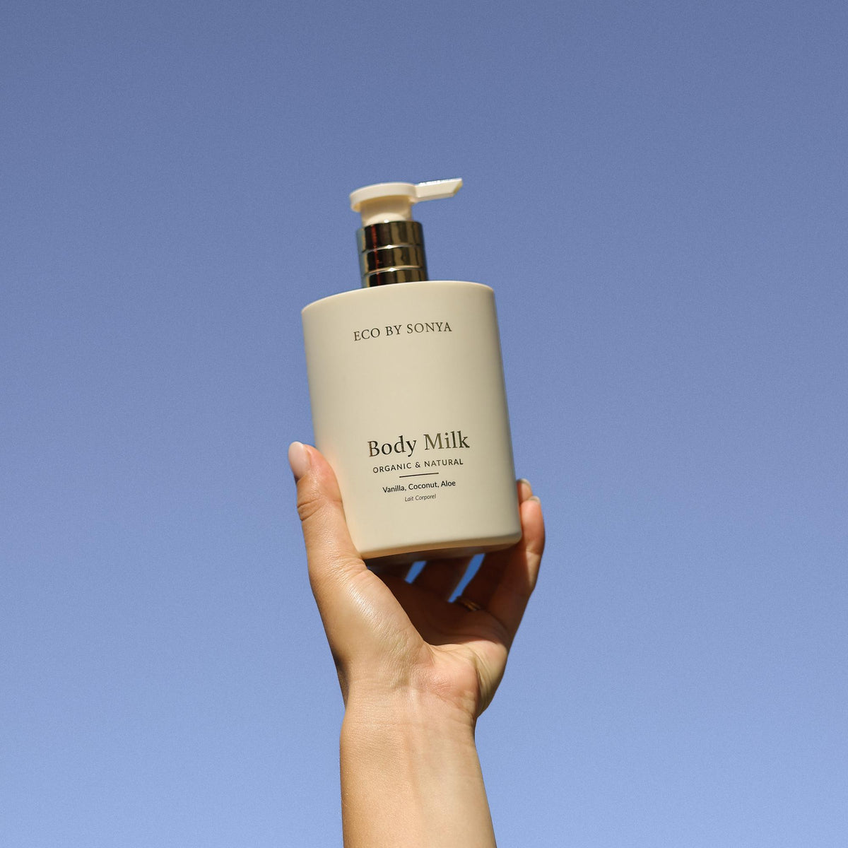 ECO BY SONYA Body Milk – Flasche in der Hand vor blauem Himmel