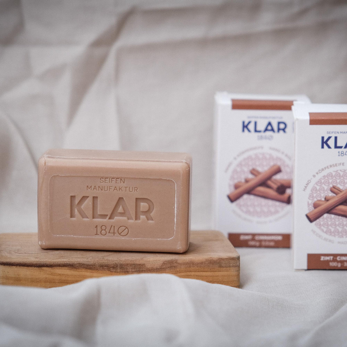 KLAR Hand- & Körperseife Zimt – Seife und Verpackung auf Leinen