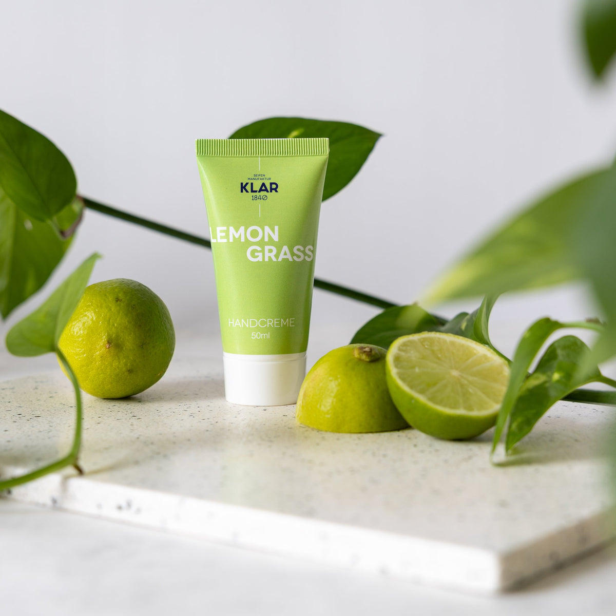 KLAR Handcreme Lemongrass – Tube auf Marmor mit Limetten