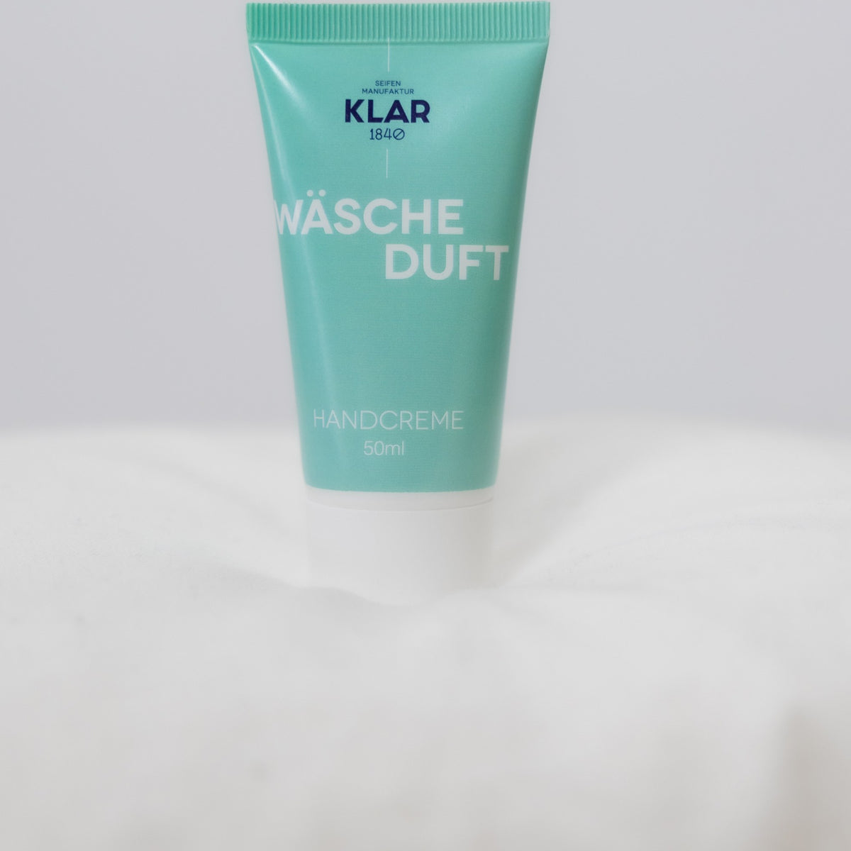 KLAR Handcreme Wäscheduft – Tube auf weißem Bettzeug