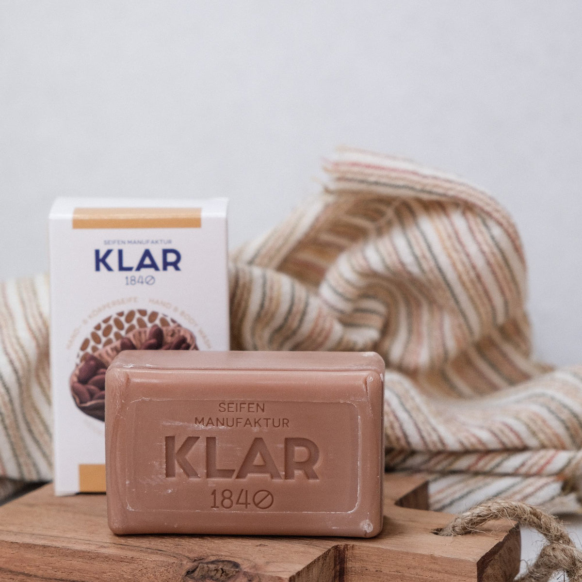 KLAR Kakaobutterseife – Seife und Verpackung auf Holzbrett