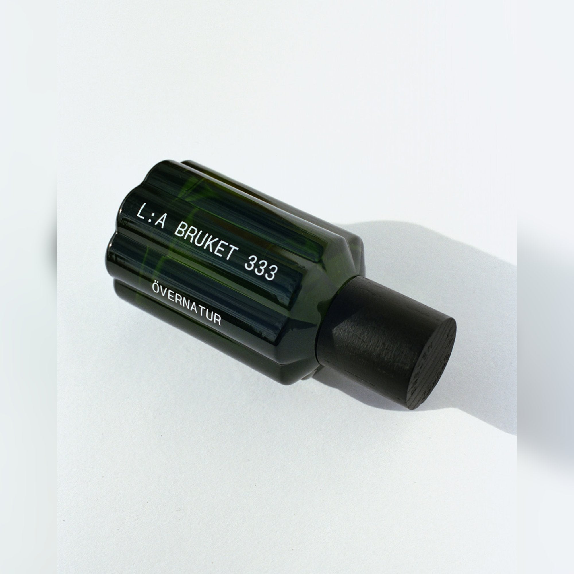 L:A BRUKET Övernatur Eau de Parfum – Flakon liegend mit Schattenwurf