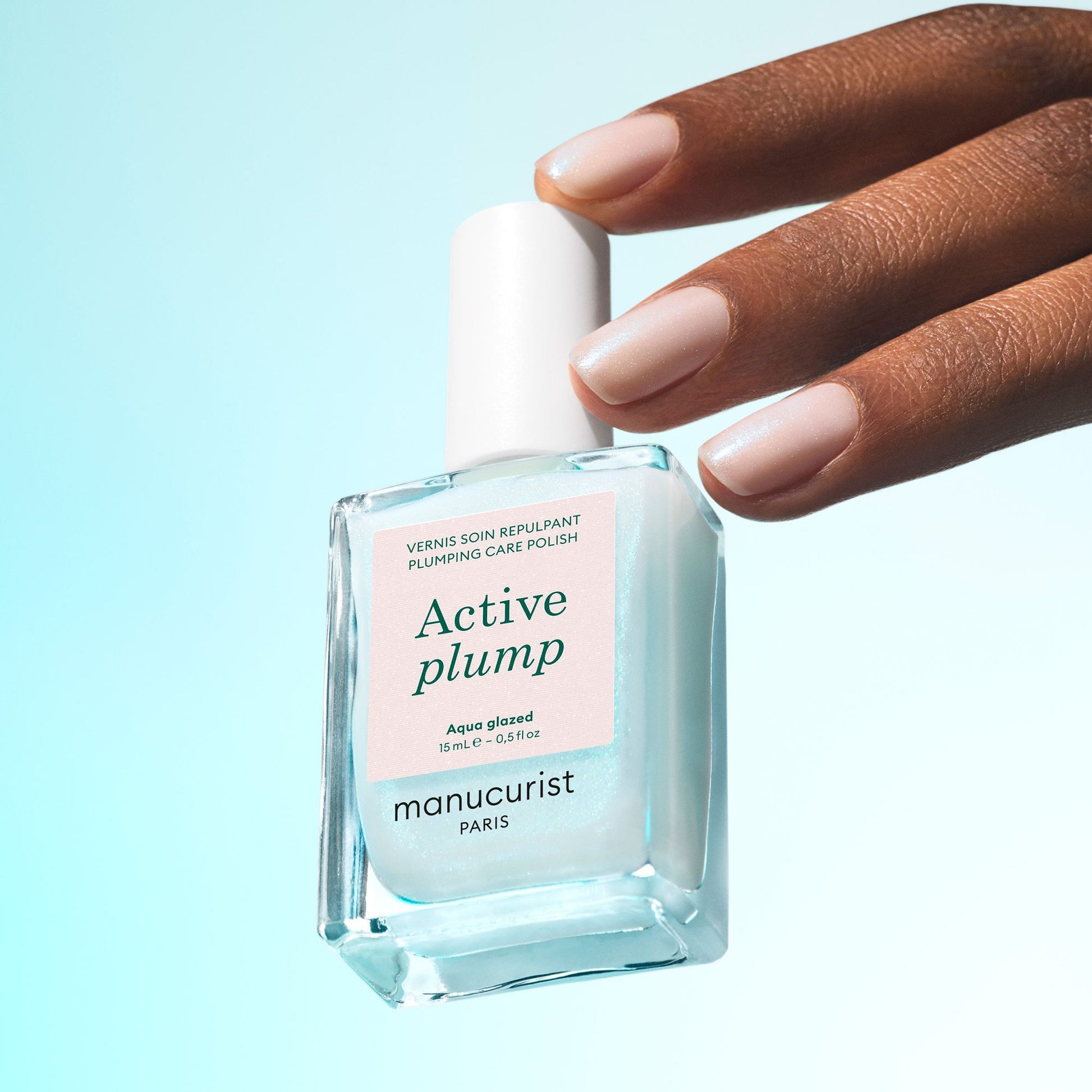 Manucurist ACTIVE Plump Aqua Glazed – Flakon vor türkisfarbenem Hintergrund
