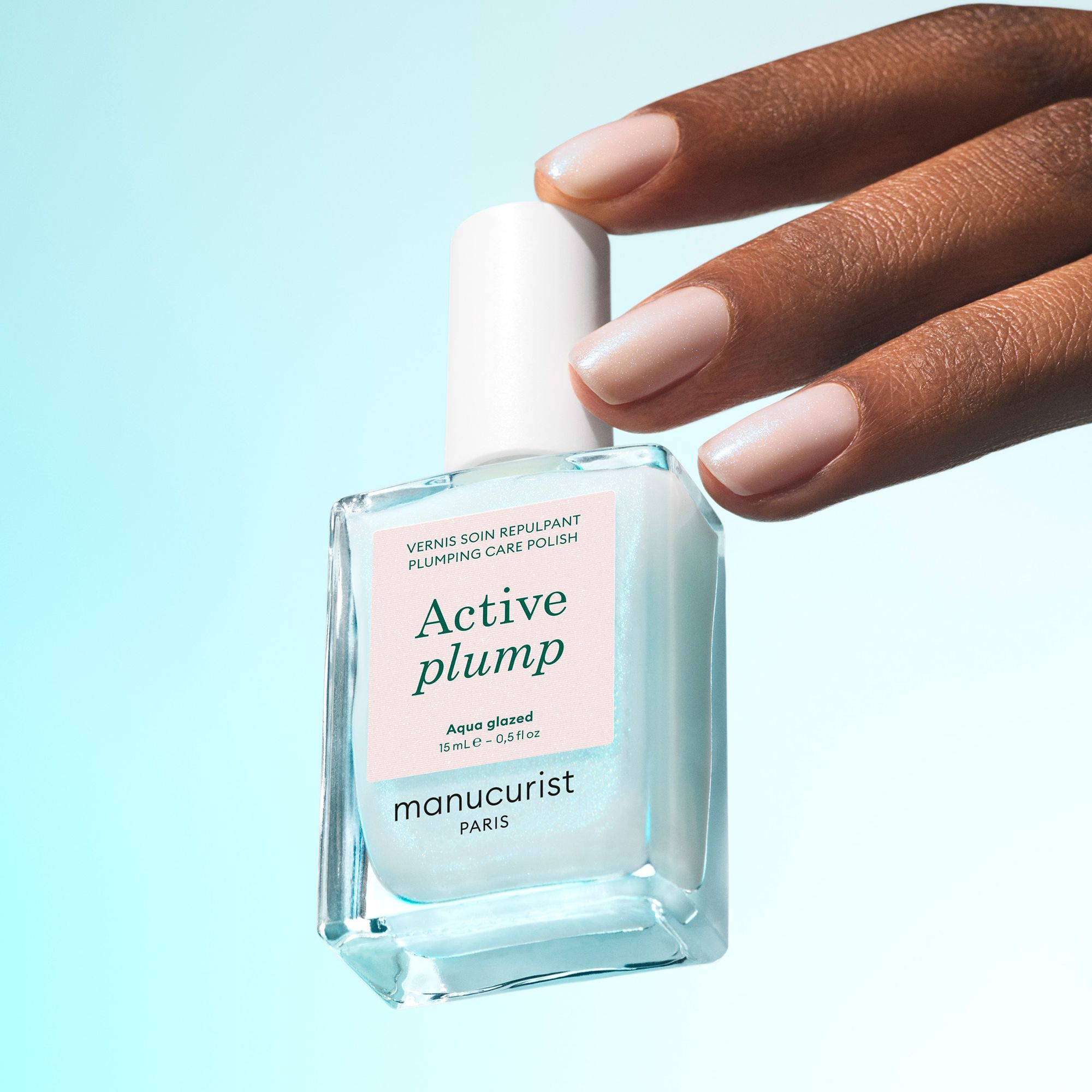 Manucurist ACTIVE Plump Aqua Glazed – Flakon vor türkisfarbenem Hintergrund