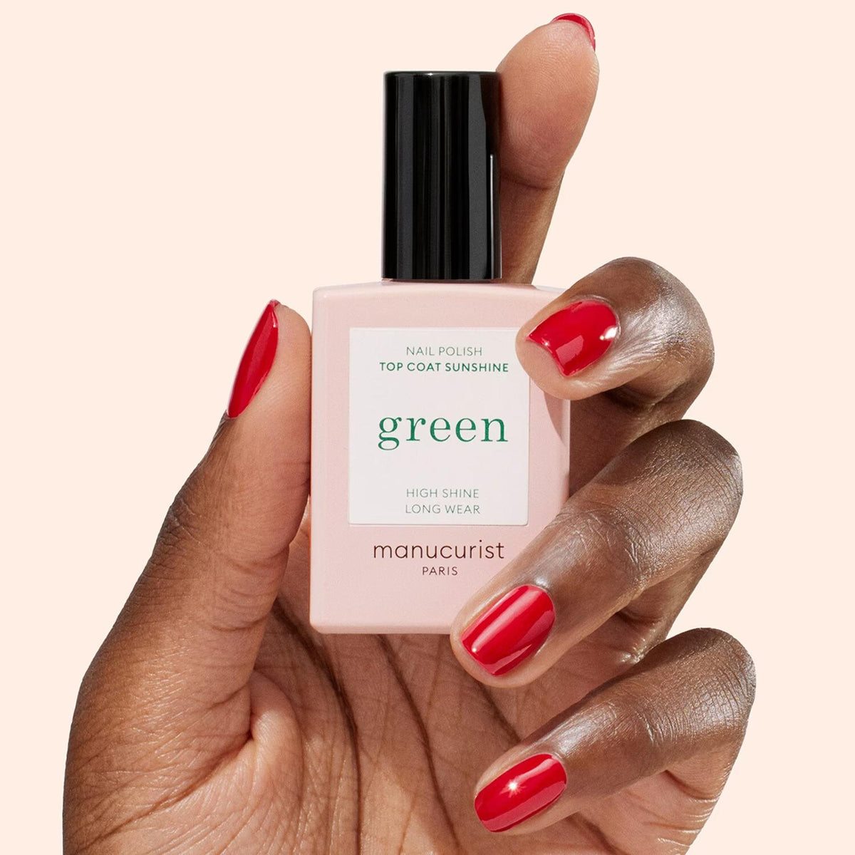 Manucurist Top Coat Sunshine – Gel-Effekt, 15ml – Flasche in der Hand mit rot lackierten Nägeln