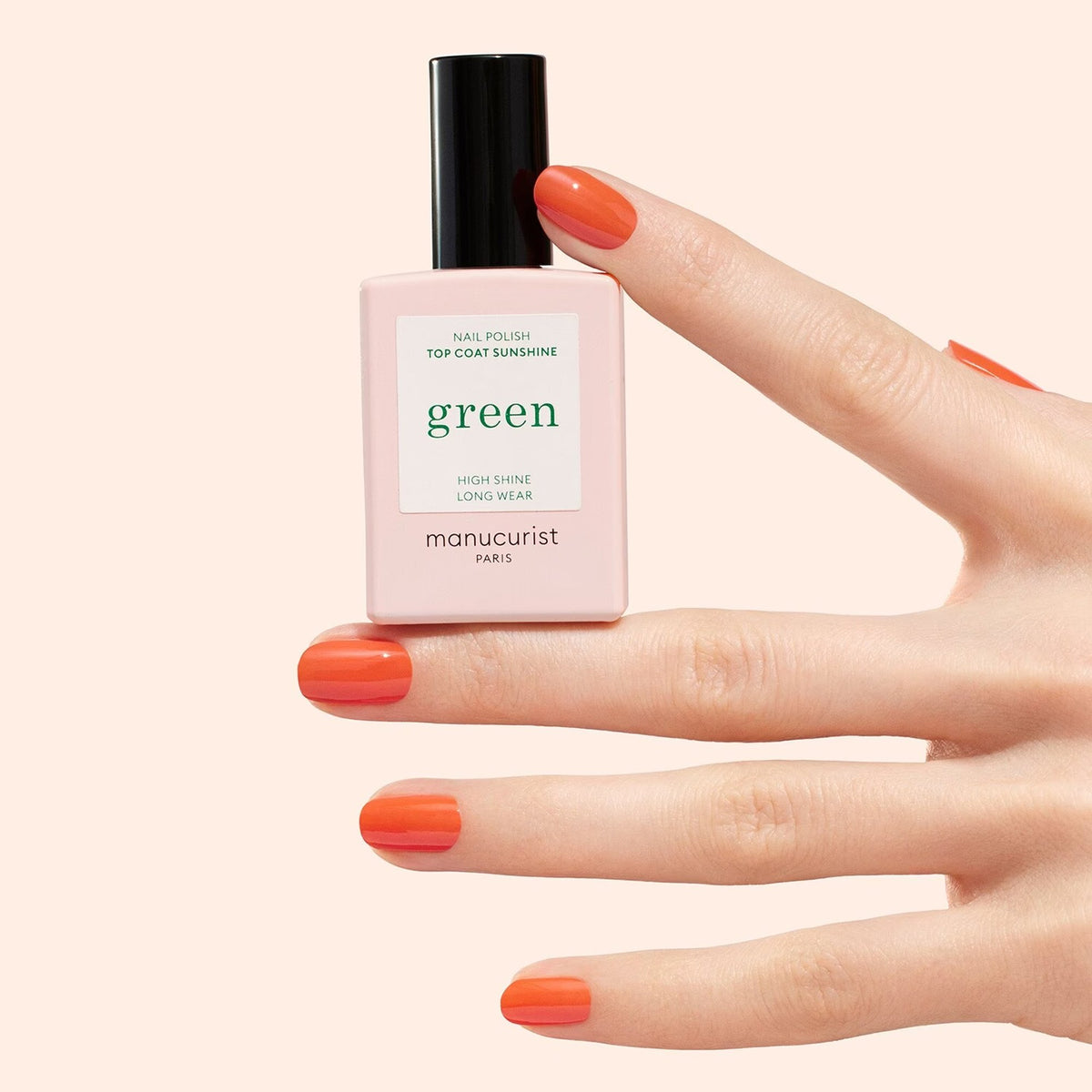 Manucurist Top Coat Sunshine – Gel-Effekt, 15ml – Flasche in der Hand mit orange lackierten Nägeln