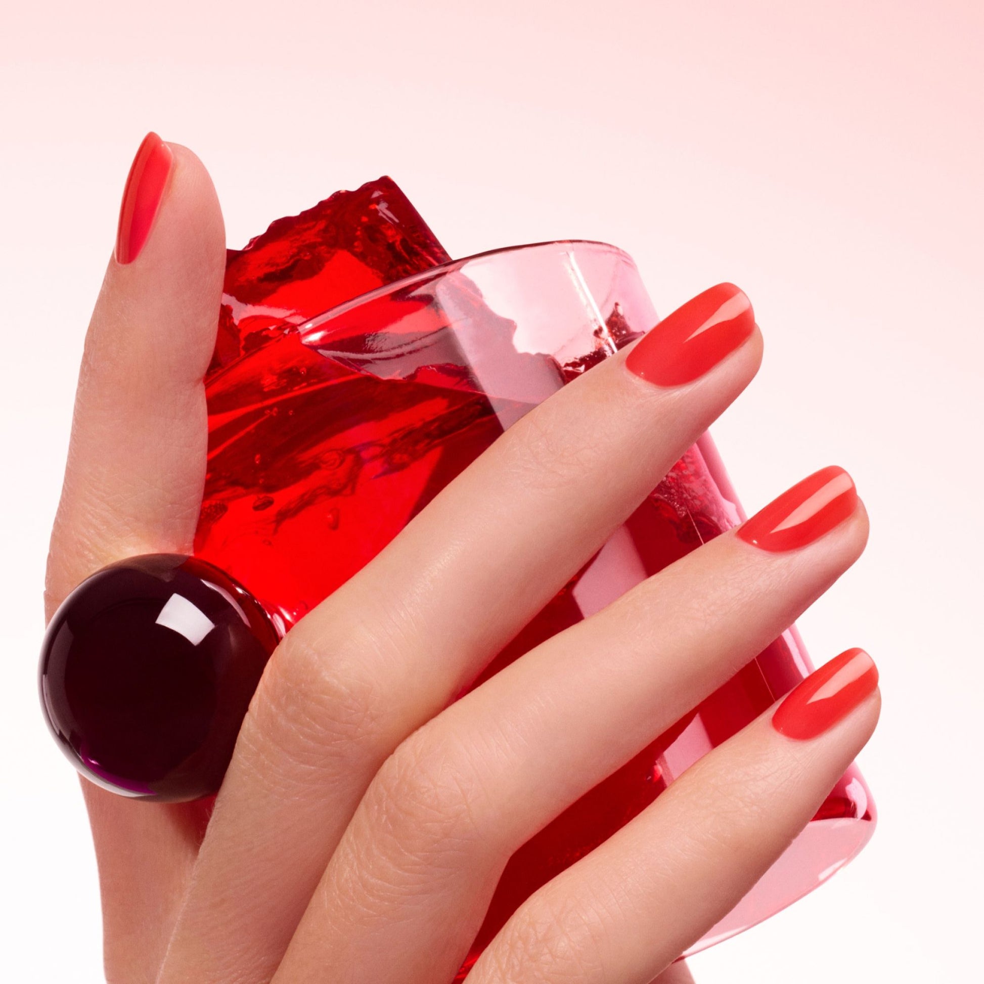 Manucurist Twizzle Jelly – Hand mit rot schimmernden Nägeln, Jelly-Finish