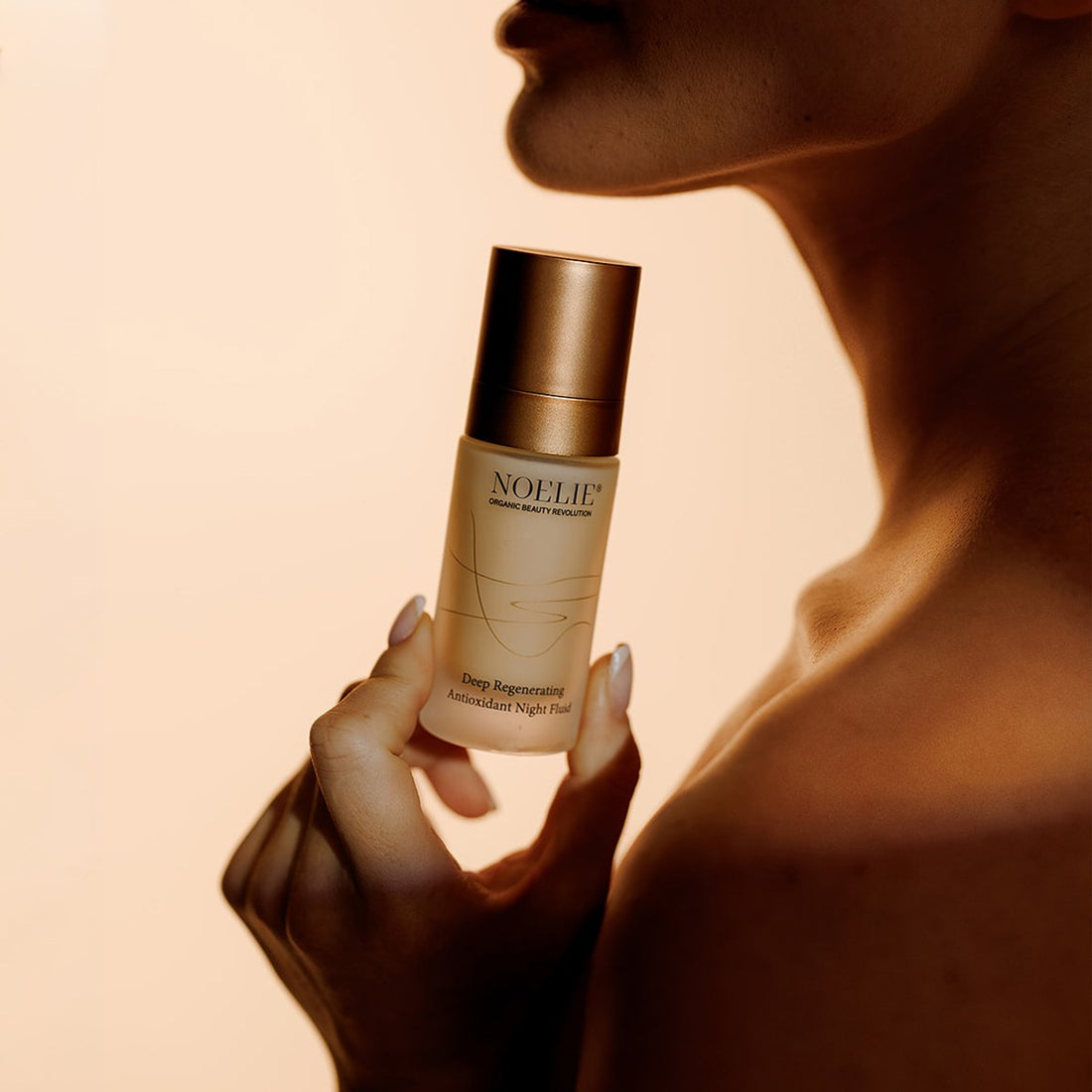 Frau hält den NOELIE Deep Regenerating Antioxidant Night Fluid – warme Lifestyle-Aufnahme