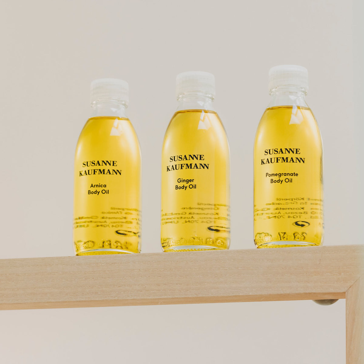 Susanne Kaufmann Arnica Body Oil / Arnika-Körperöl, 100ml – drei Körperöle der Linie auf einem Wandregal