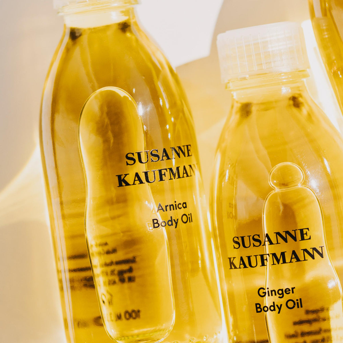 Susanne Kaufmann Arnica Body Oil / Arnika-Körperöl, 100ml – Flaschen im Sonnenlicht