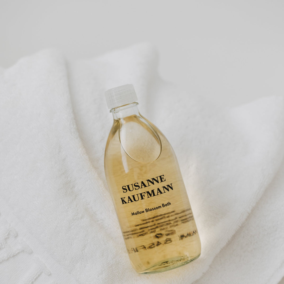 Susanne Kaufmann Mallow Blossom Bath / Malvenblütenbad, 250ml – Flasche auf einem weißen Handtuch
