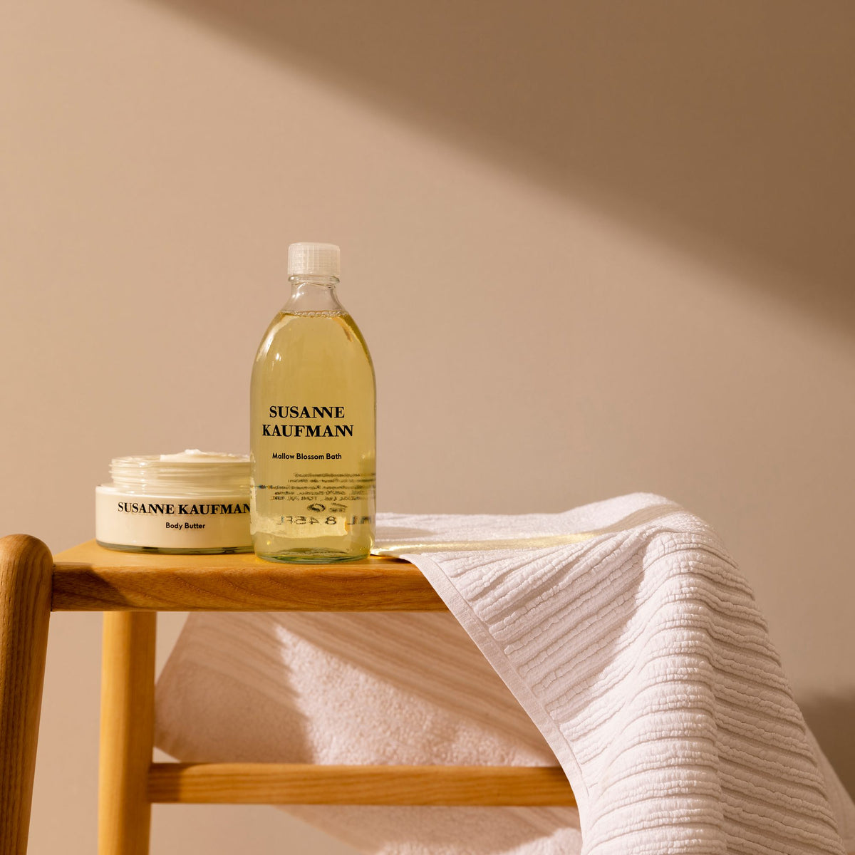 Susanne Kaufmann Mallow Blossom Bath / Malvenblütenbad, 250ml – Flasche auf einem Holzhocker