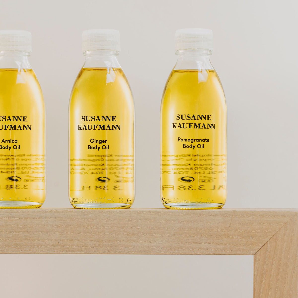 Susanne Kaufmann Pomegranate Body Oil / Granatapfel-Körperöl, 100ml – mit Arnika- und Ingwer-Körperöl auf einem Holzregal