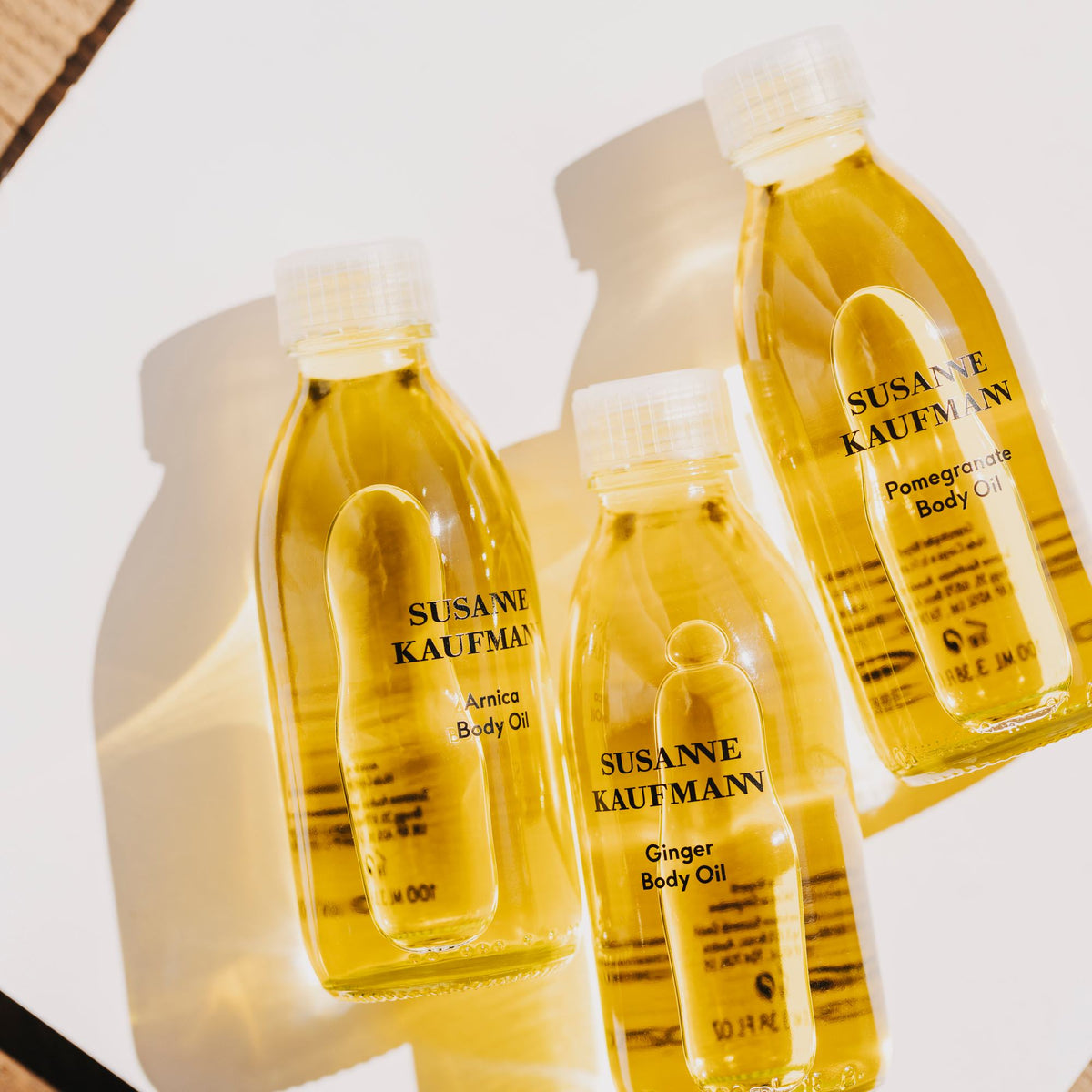 Susanne Kaufmann Pomegranate Body Oil / Granatapfel-Körperöl, 100ml – drei Körperöle der Linie im Sonnenlicht