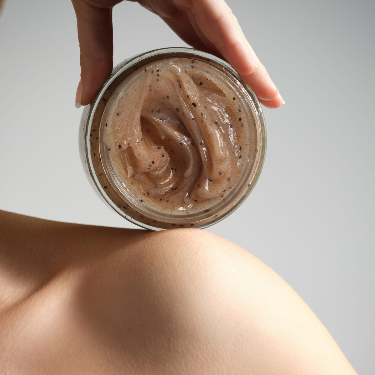 Susanne Kaufmann Refining Scalp & Body Scrub / Peeling für Körper & Kopfhaut, 200ml – Tiegel in der Hand an der Schulter