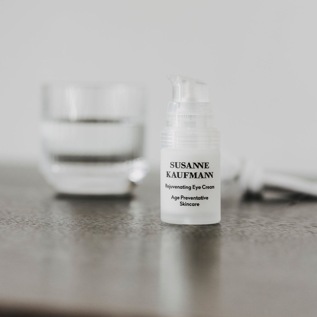 Susanne Kaufmann Rejuvenating Eye Cream / Augencreme, 15ml – Spender auf einem dunklen Tisch