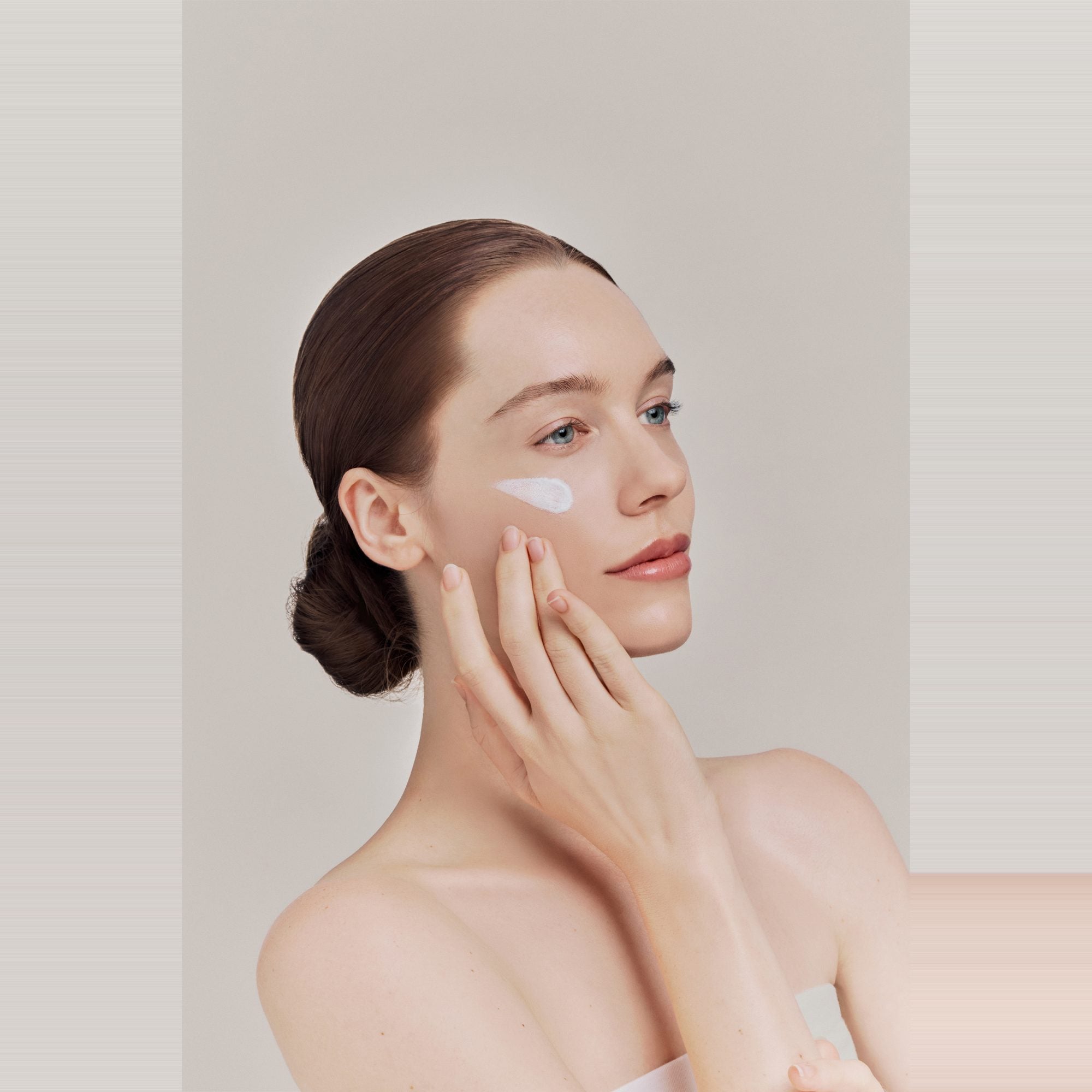 Frau verteilt die Pear Blossom Sunscreen auf der Wange